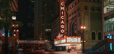 The iconic Chicago Theatre marquee shines brightly at night on a city street.