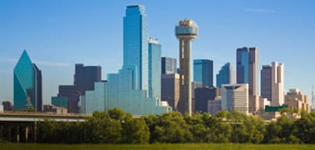 Dallas skyline with modern skyscrapers and Reunion Tower under a clear blue sky.