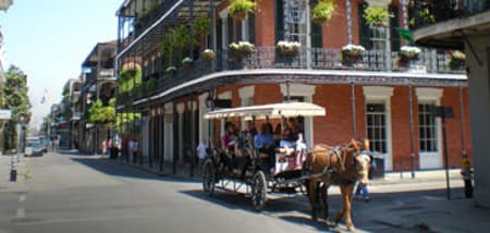 Horse-drawn carriage with tourists on a historic street in New Orleans, Louisiana.