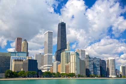 Chicago skyline with tall skyscrapers along the waterfront under a cloudy blue sky.