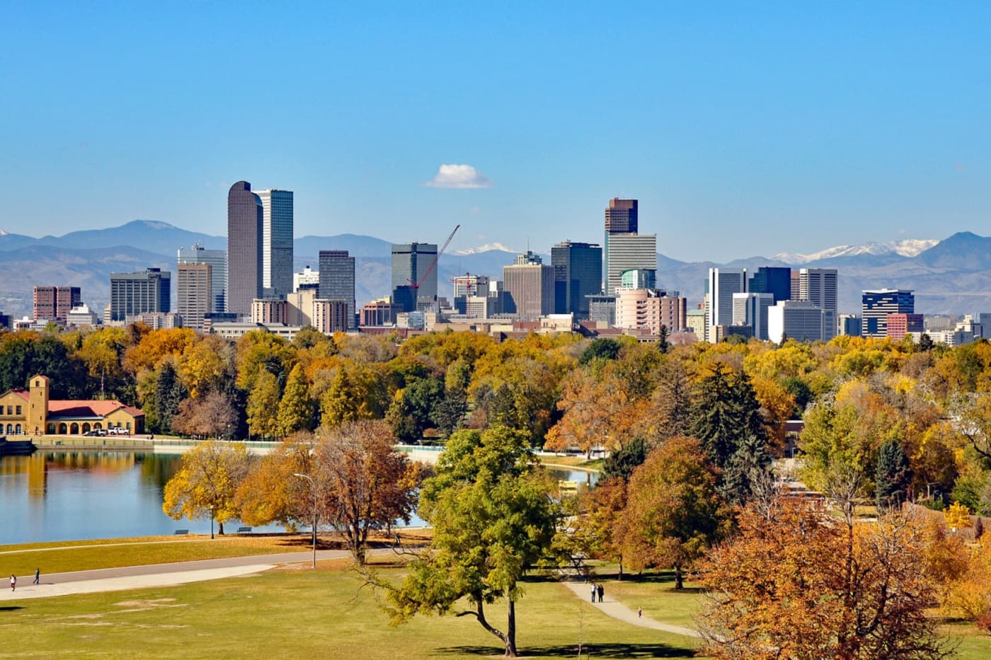 City skyline, autumn trees, and a lake with mountains in the background.