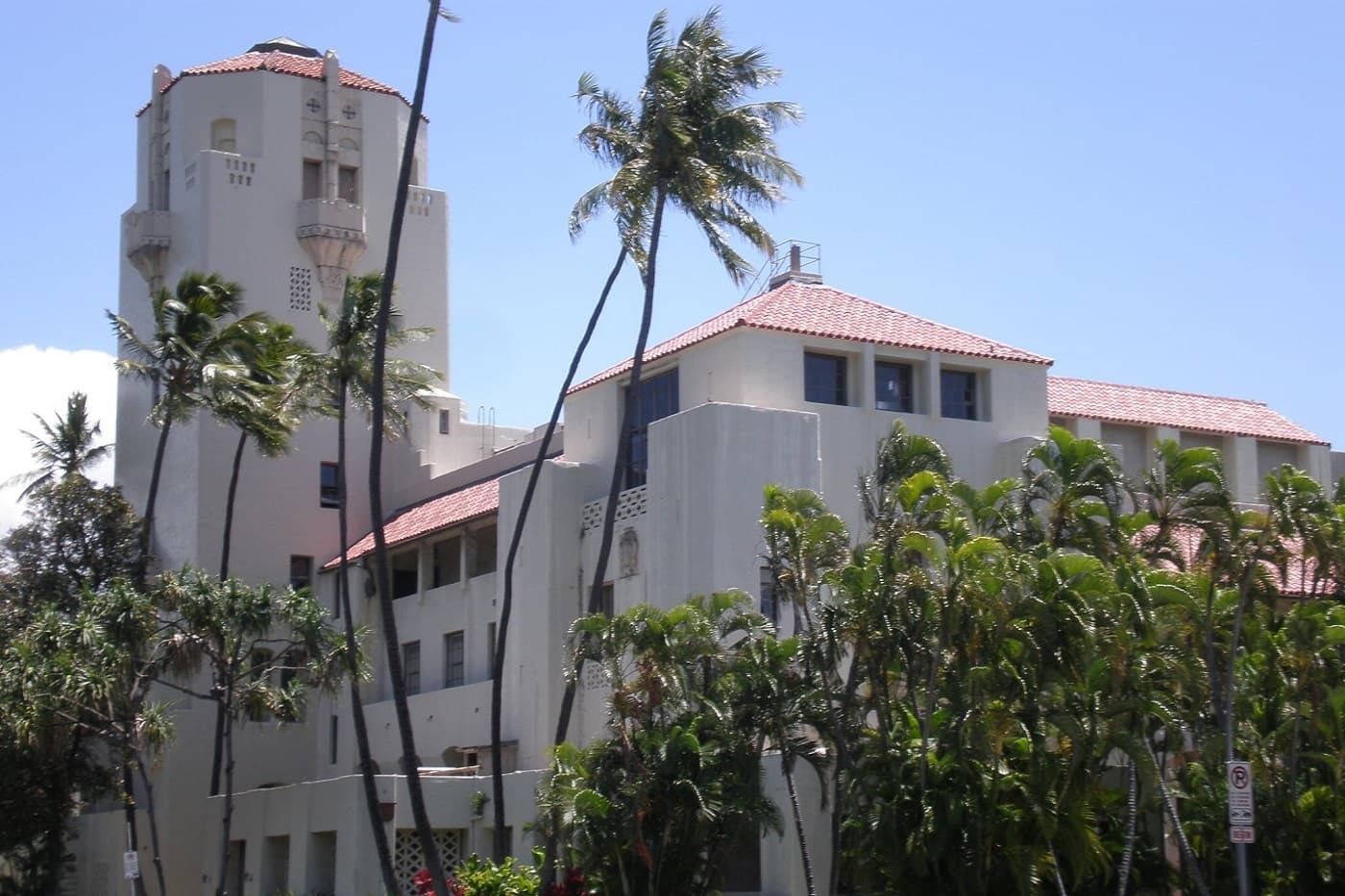 Historic white building with a Spanish Colonial tower surrounded by tall palm trees.