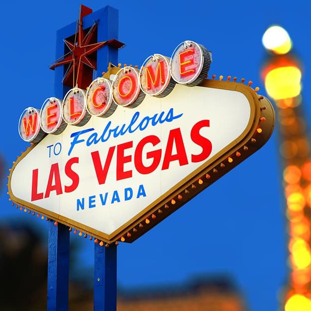 Iconic 'Welcome to Fabulous Las Vegas Nevada' sign illuminated against a blue sky.