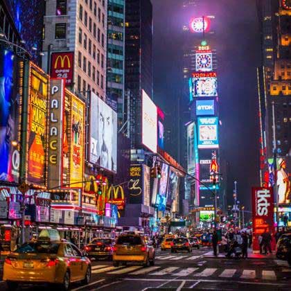 Times Square at night with illuminated billboards, skyscrapers, and yellow taxis on the street.