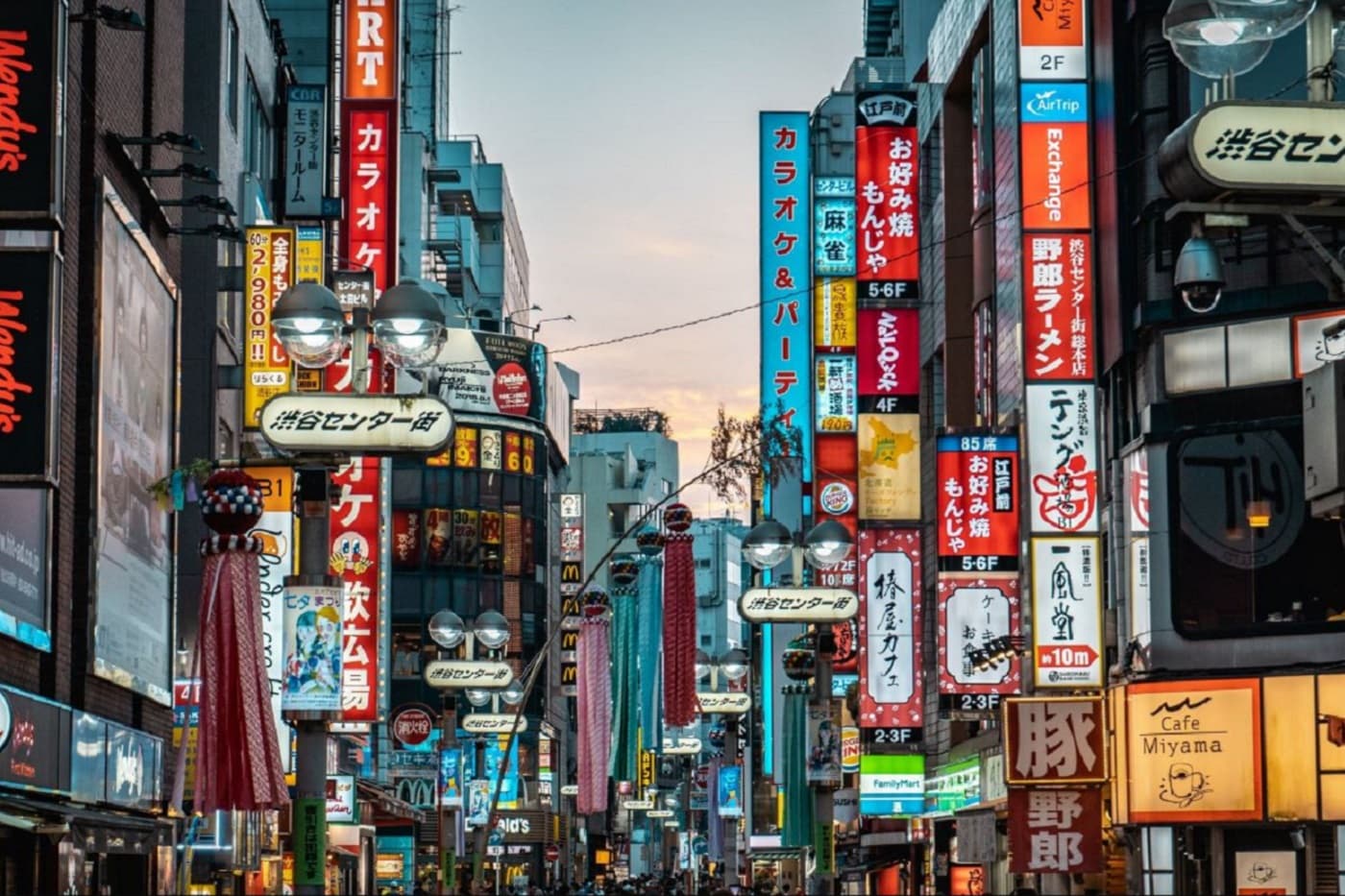Vibrant Japanese city street at night, illuminated by numerous colorful neon signs.