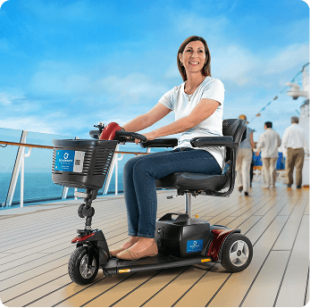 Woman on a red mobility scooter smiles on a cruise ship deck with ocean in background.